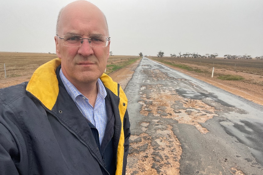 politician standing in front of bad road