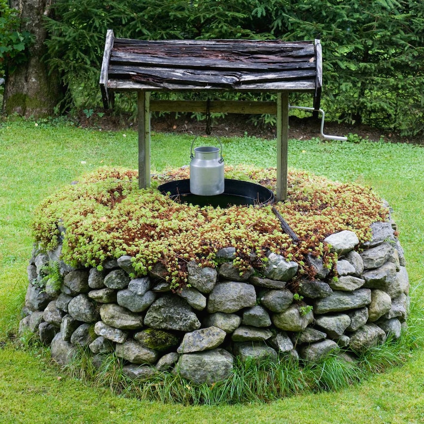 A traditional Norwegian stone wishing well with small metal pail