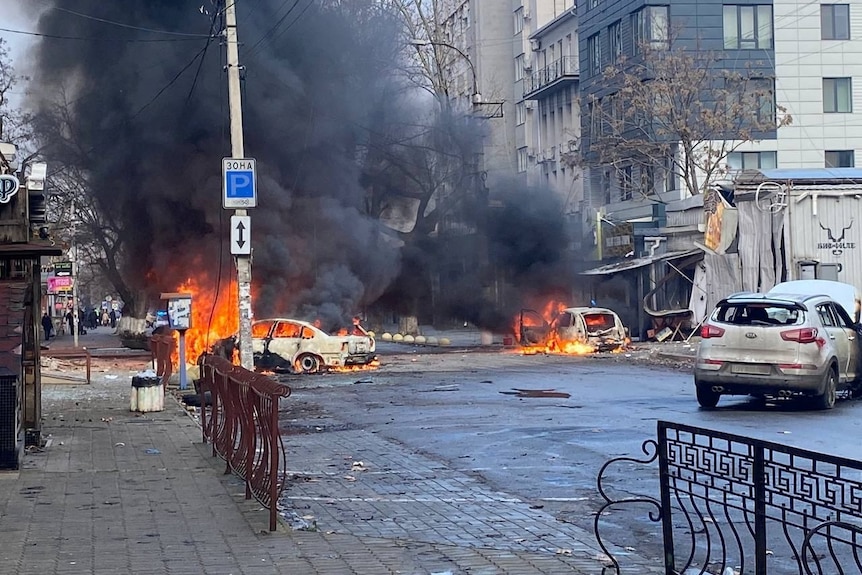 Cars burn on a street after a Russian military strike.