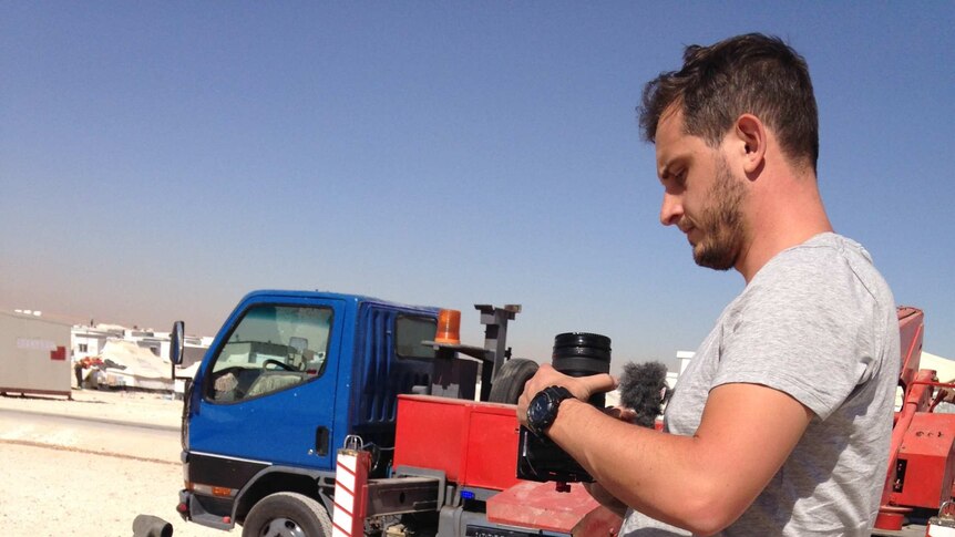 A child watches as a journalist prepares to film at Zaatari camp in Jordan