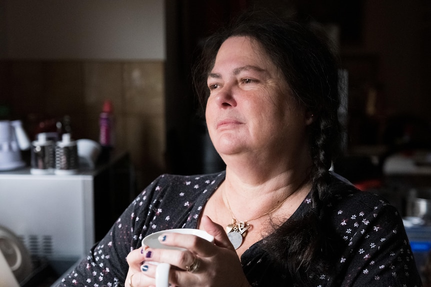 A close up of a woman holding a cup of tea in her hands.