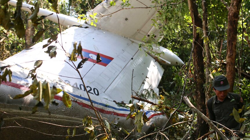 Rescue worker makes his way past the wreckage of an air force plane crash in Laos