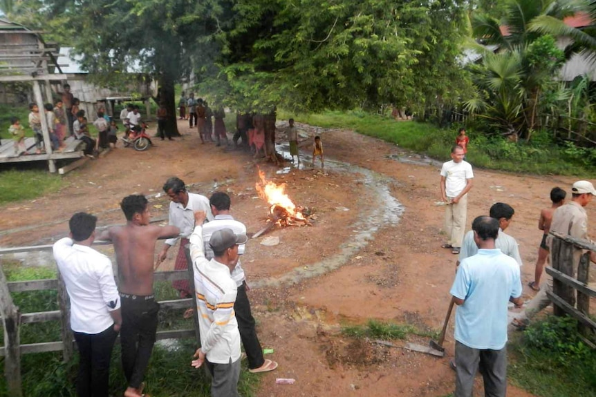 Residents gather round as confiscated chainsaws are set on fire.