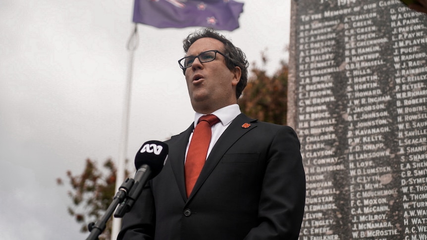 man stands in front of war memorial