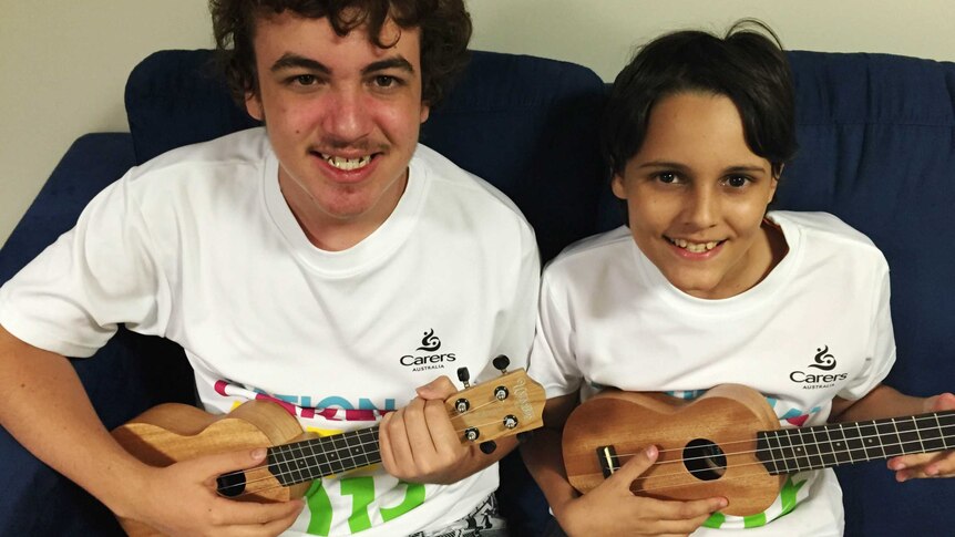 two boys holding small guitars