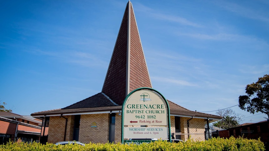 A cross sits atop a brick-tile church spire.