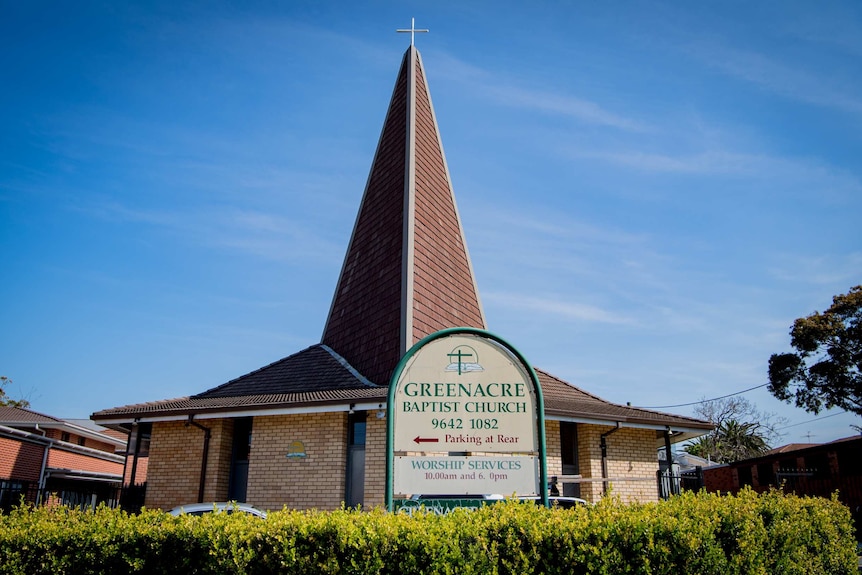 A cross sits atop a brick-tile church spire.