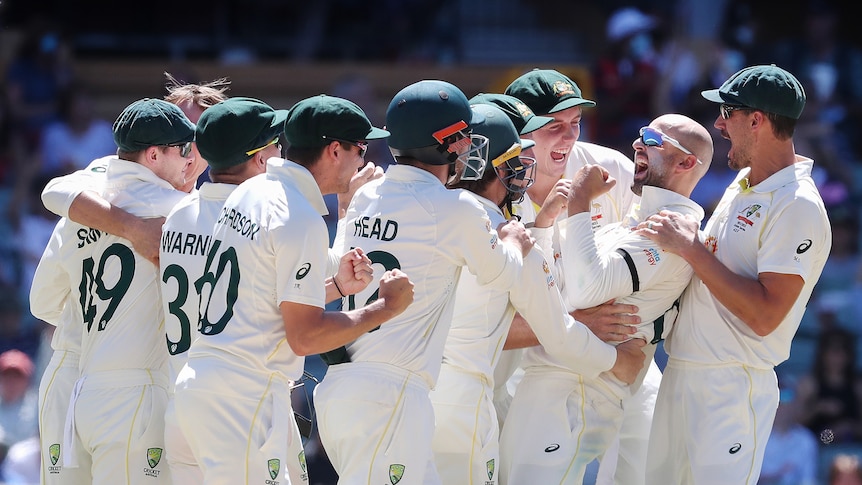 The entire Australian team gathers around Nathan Lyon, who has a big smile on his face