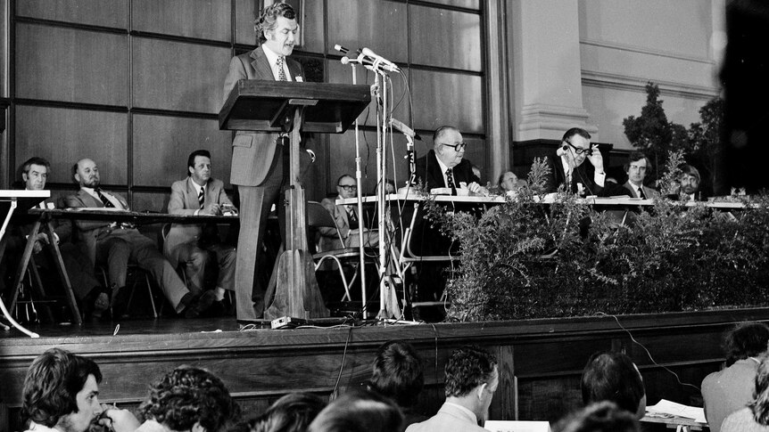 Bob Hawke stands at a lectern addressing the Biennial Congress of Trade Unions in 1975.