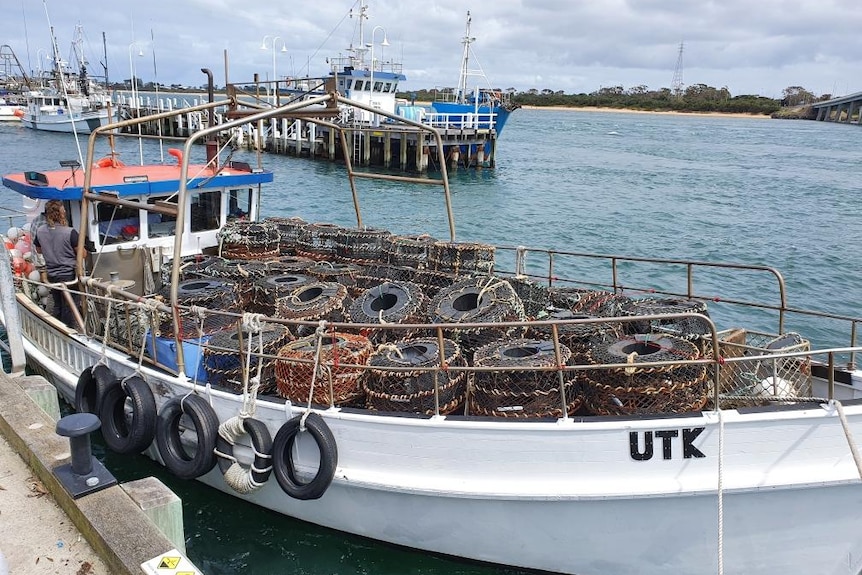 fishing boat docked in harbour with fishing nets 