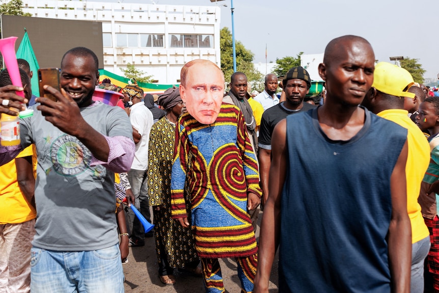 A protest in Africa where one person is wearing a Vladimir Putin mask.