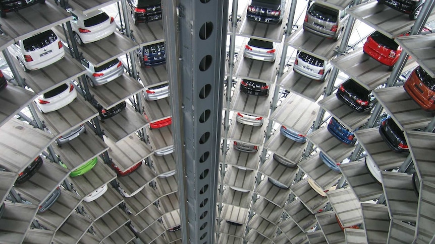 cars parked inside a deep cylindrical automated parking garage with dozens of levels