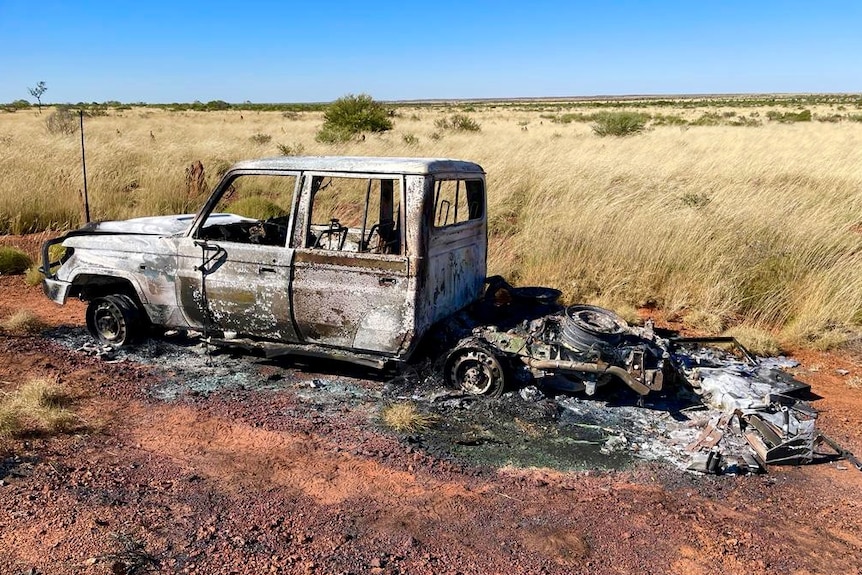 A 4WD vehicle gutted by car sits abandoned on a grassy bush track