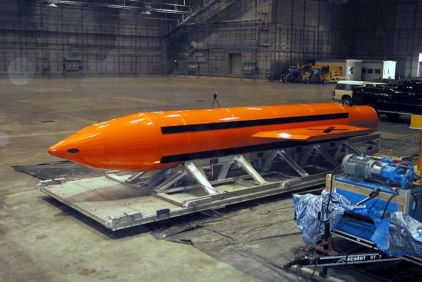 An orange GBU-43 bomb in a large warehouse.