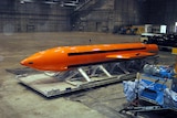An orange GBU-43 bomb in a large warehouse.