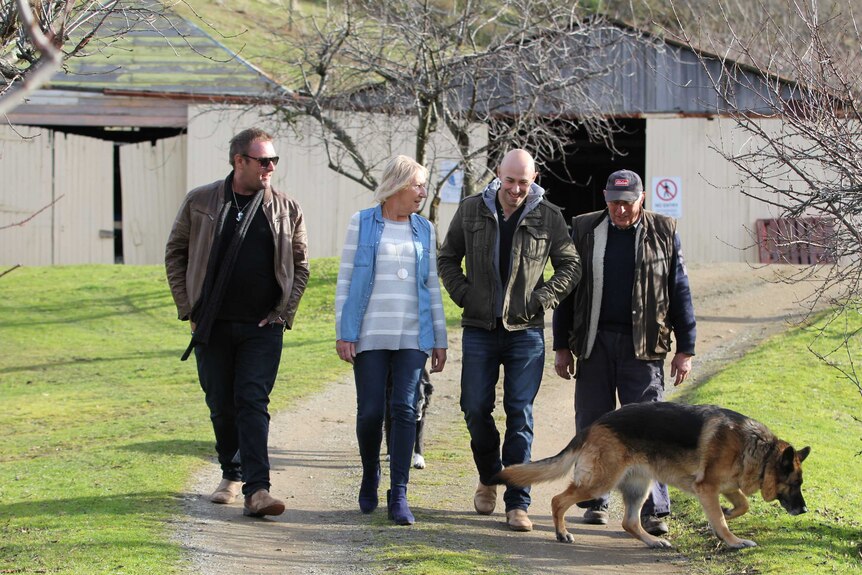 Tom Wolfe, Leigh Wolfe, Nick Wolfe and Tony Wolfe walk in a line with a dog.