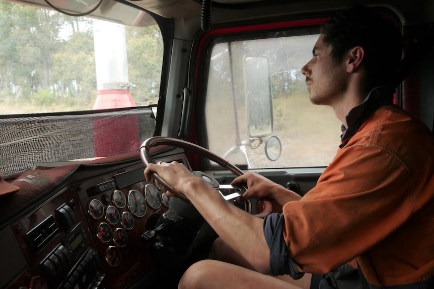 A man in high-vis behind the wheel of a truck.