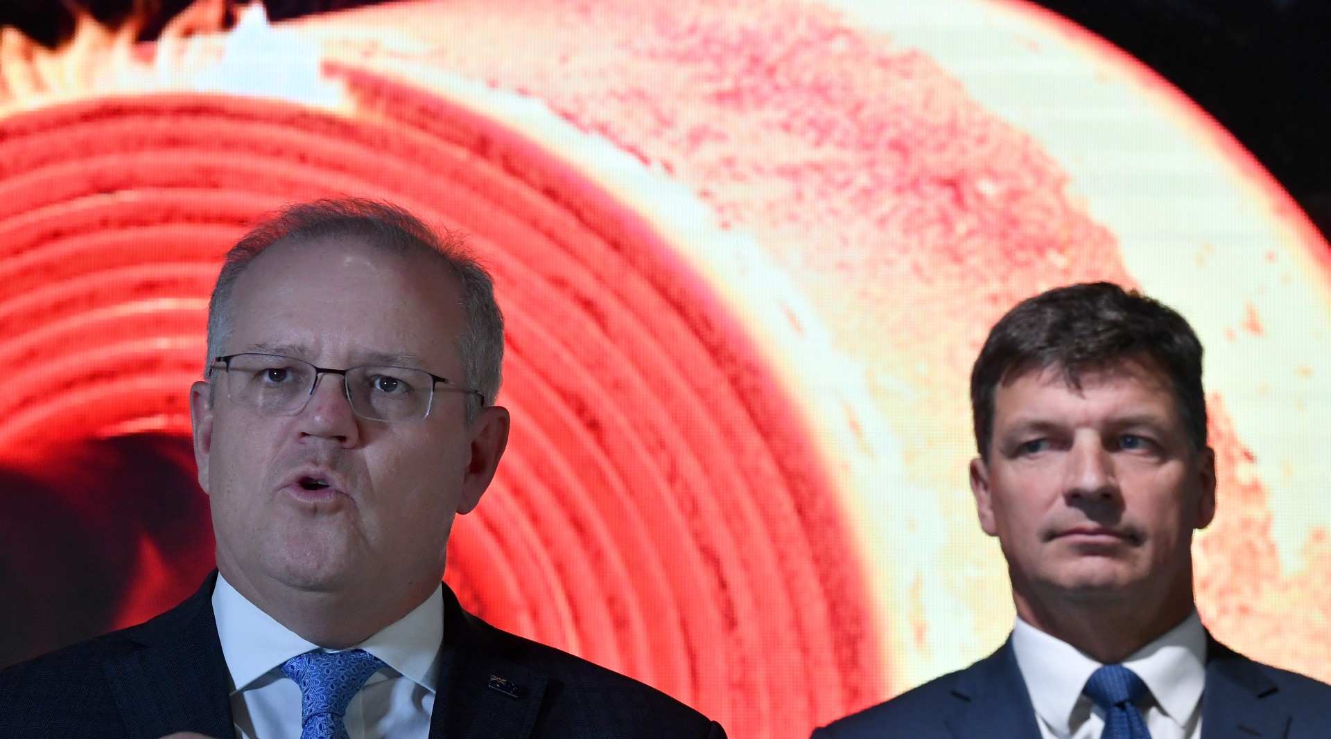 The Prime Minister and Angus Taylor at a media event with a red background.