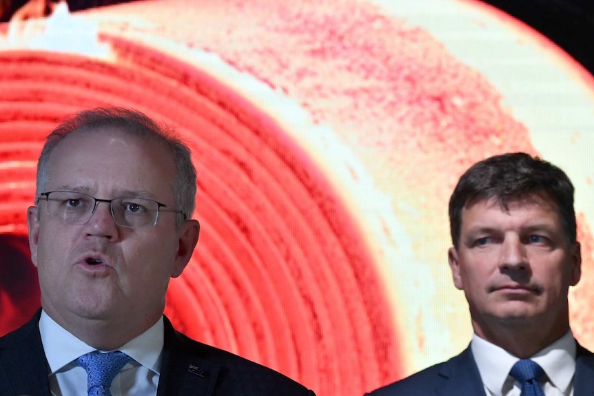 The Prime Minister and Angus Taylor at a media event with a red background.