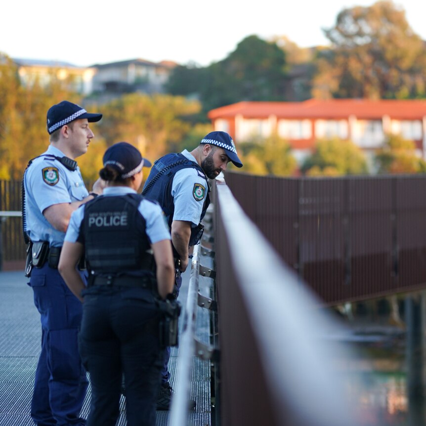 Police tape in front of a river and a bridge in the distance / police looking over the edge of a bridge with a river below