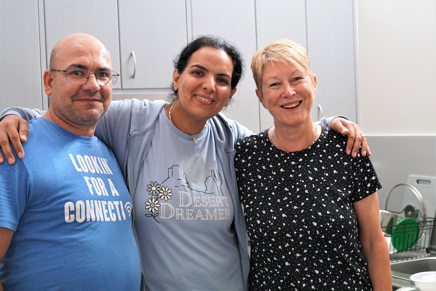 Two syrian adults with an Australian in a kitchen.