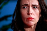 Jacinda Ardern with a bold rep lip looking sombre 