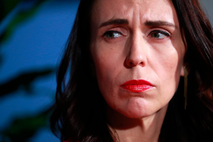 Jacinda Ardern with a bold rep lip looking sombre 