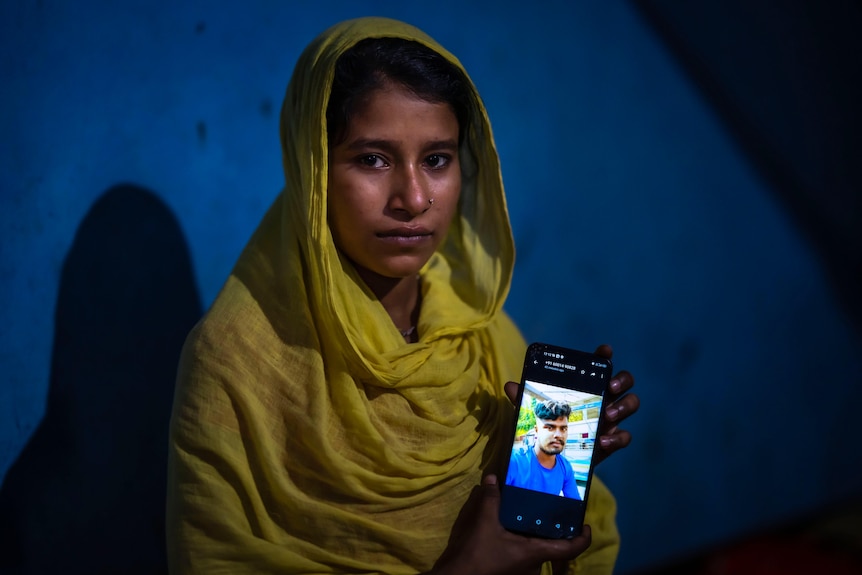 Underage girl holds up phone showing image of her husband who was arrested by police.