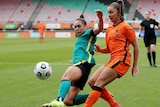 Female soccer players chasing down a ball with the opposition player behind her as they race for the ball during a match