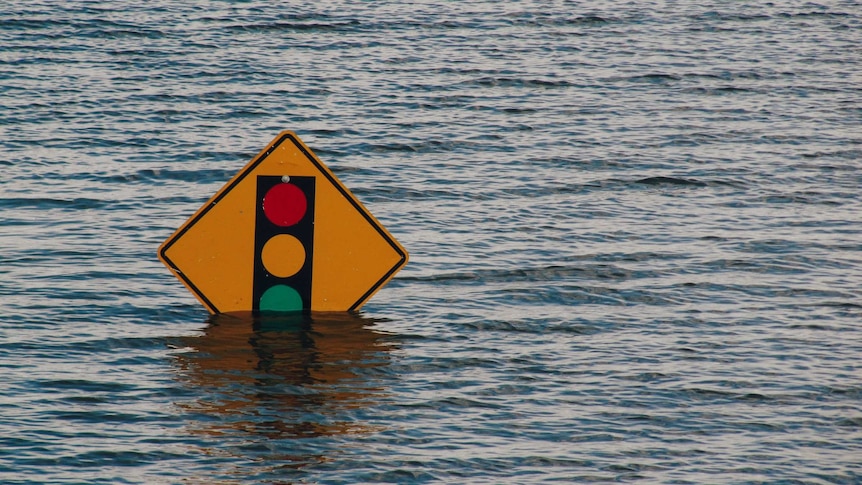 A flooded road in Davenport, Iowa. Only a traffic light sign is visible, with the water lapping at the edge of the sign.