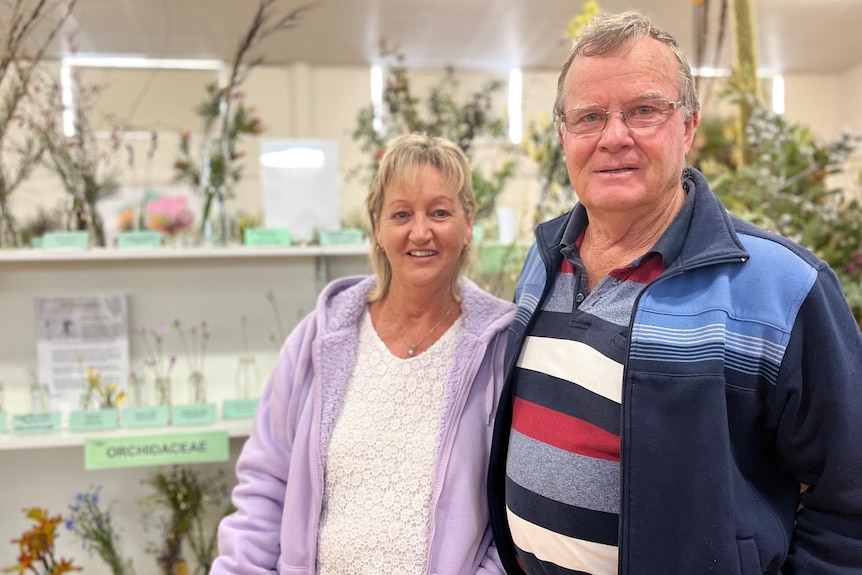 two people standing in front of flowers