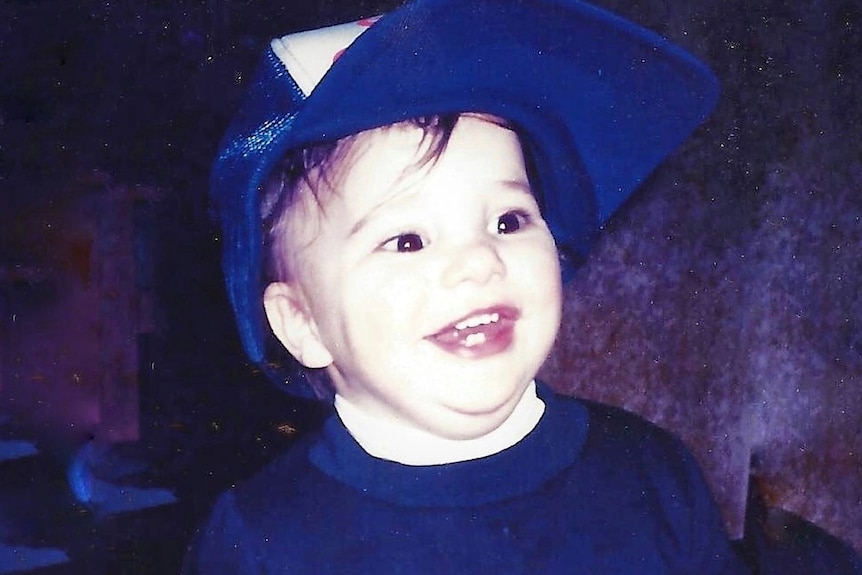 a young boy smiling and wearing a cap