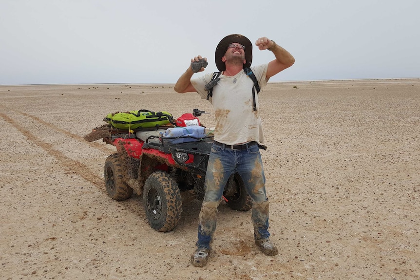 Curtin University Professor Phil  Bland threw his fists in the air, holding an ancient meteorite in front of a quad bike.