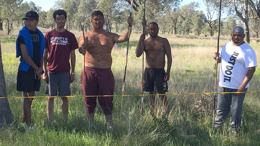 A group of protestors stand in a site marked for construction