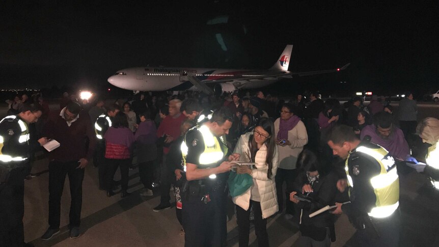 Passengers talk to police on the tarmac near the Malaysia Airlines plane.