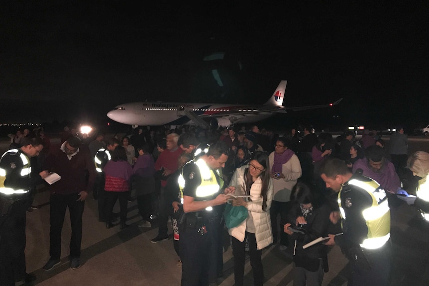 Passengers talk to police on the tarmac near the Malaysia Airlines plane.