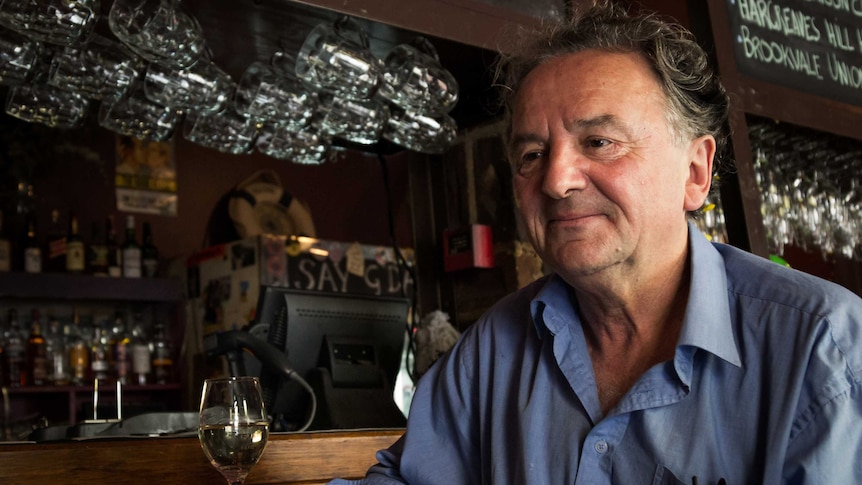 Louis Nowra sits with a glass of wine at the front of a bar