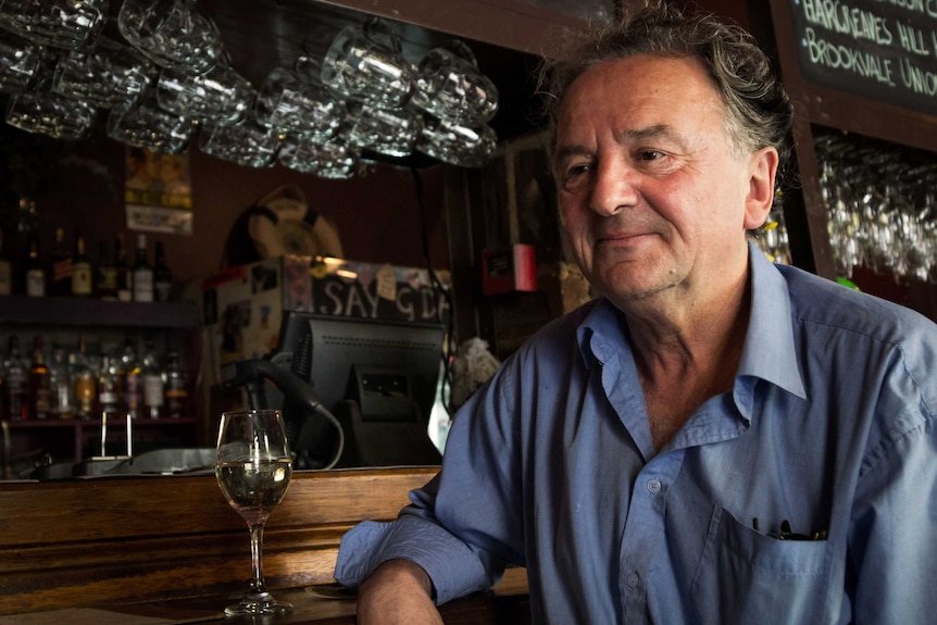 Louis Nowra sits with a glass of wine at the front of a bar