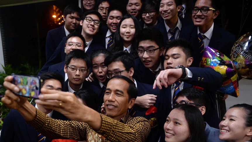 Indonesian President Joko Widodo takes a selfie with classmates of his youngest son