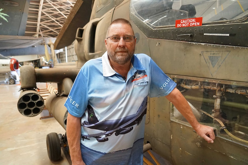 Tony Simons is standing next to an aircraft at the Darwin Aviation Museum. He is wearing glasses and a work uniform.