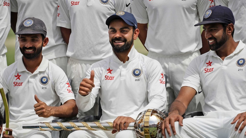 India's captain Virat Kohli gestures as the team poses with the Border-Gavaskar Trophy.