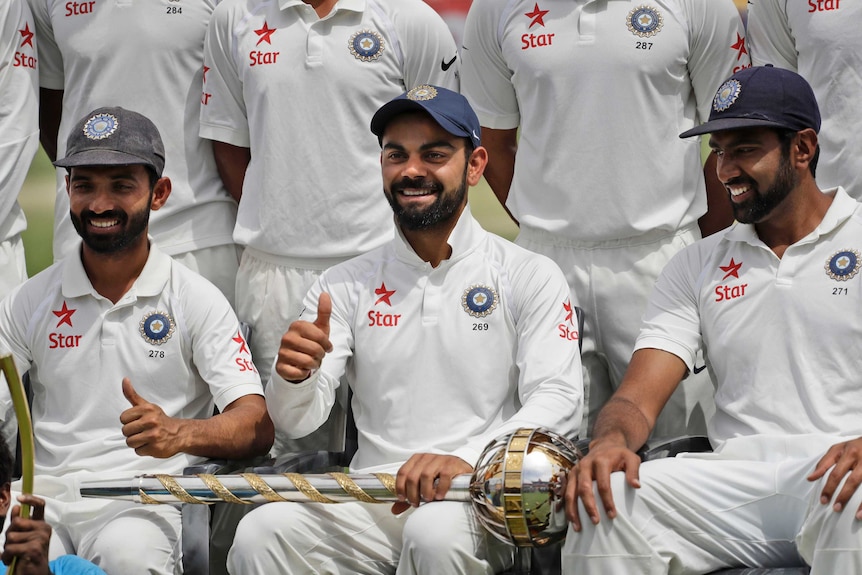 India's captain Virat Kohli gestures as the team poses with the Border-Gavaskar Trophy.
