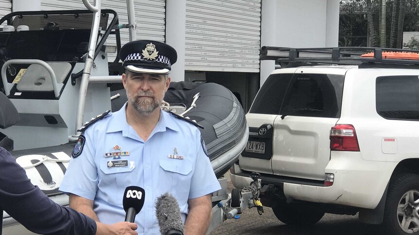 Chief superintendent Brian Huxley of Queensland police stands in front of a boat.