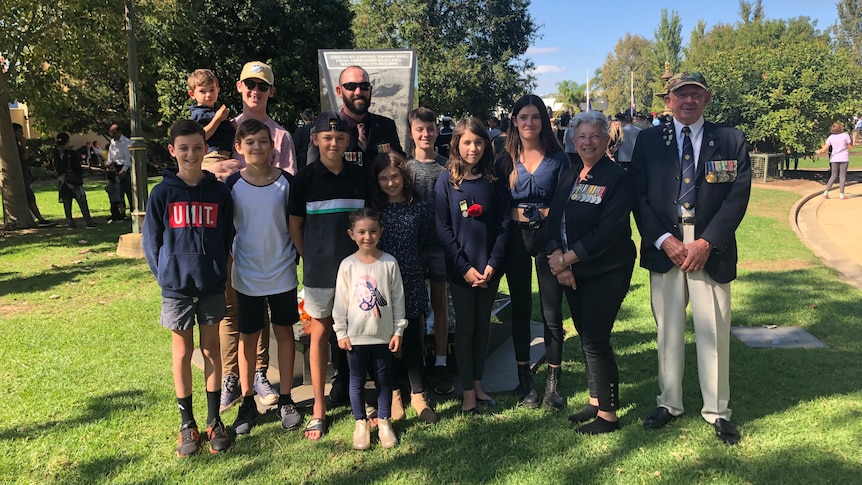 A large group of children and adults pose for a photograph on Anzac Day.