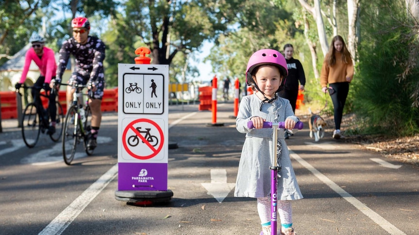 A child on a scooter, people cycling and walking.