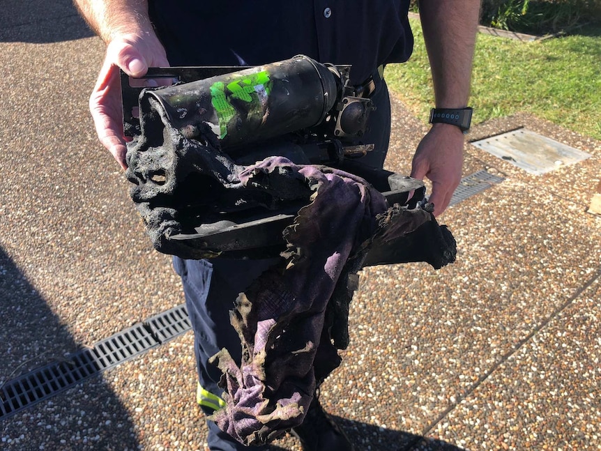 A fireman holds the melted remnants of butane heater that exploded causing a house fire.