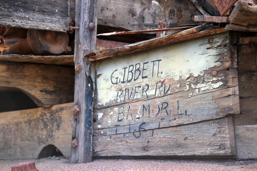 Gordon Ibbett's name and address printed on the side of an old truck on wood.