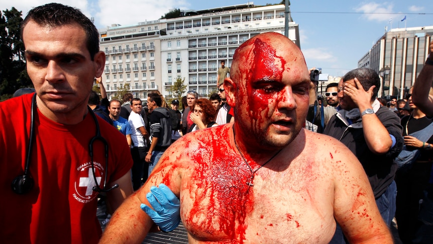 A man covered in his own blood escapes a protest in Athens
