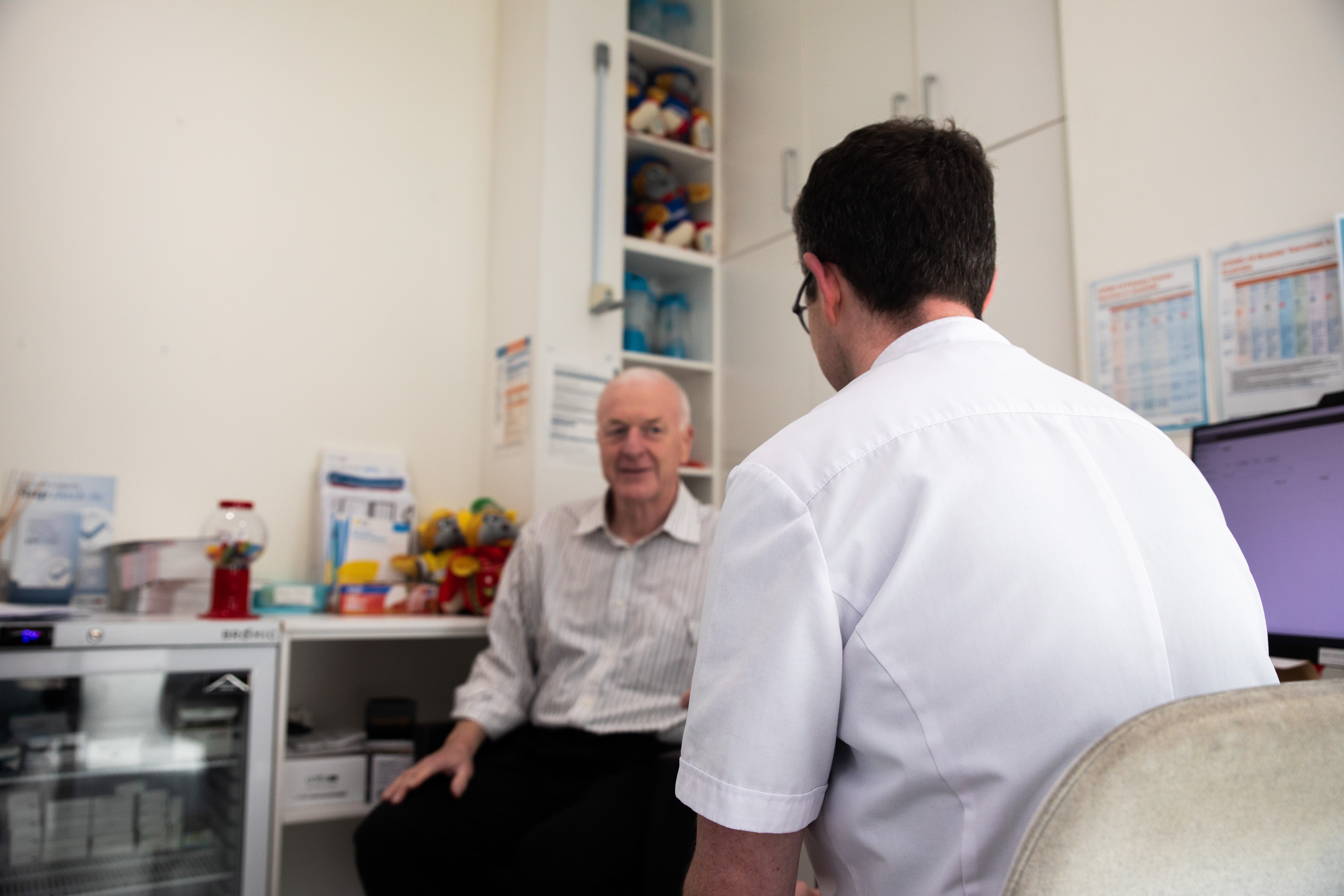 A pharmacist speaks to a patient in a small room.
