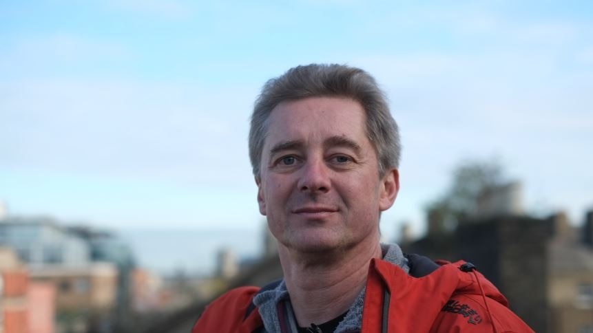 Man in a red jacket with city in the background